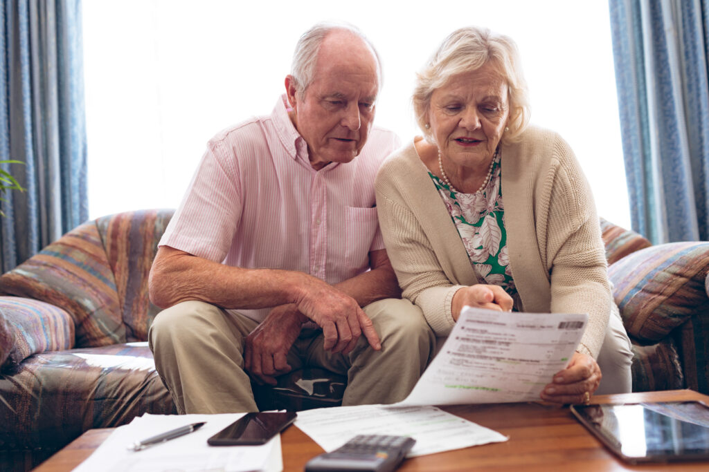 Front view of senior Caucasian couple discussing over medical bill while sitting on vintage sofa at retirement home